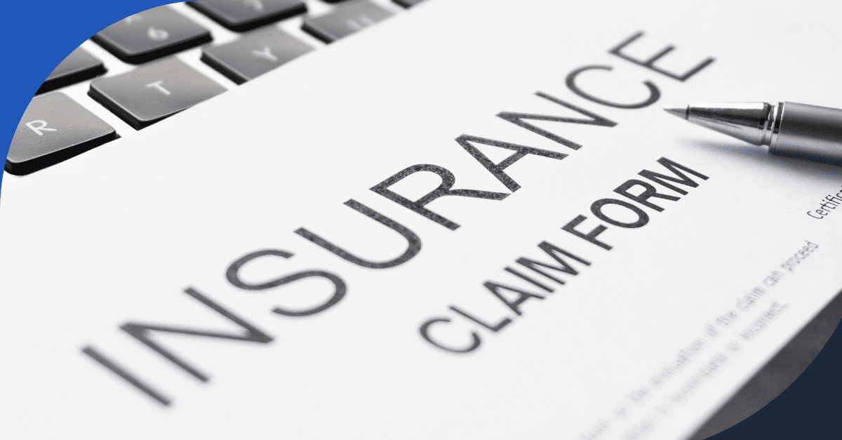Close-up of an insurance claim form with a pen and laptop keyboard in the background.