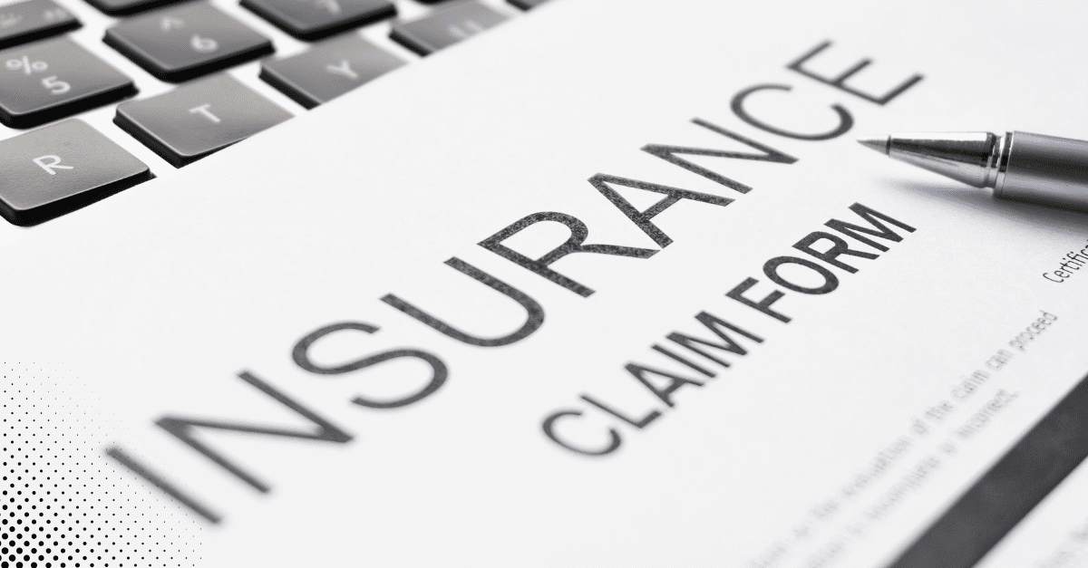 Close-up of an insurance claim form with a pen and computer keyboard.
