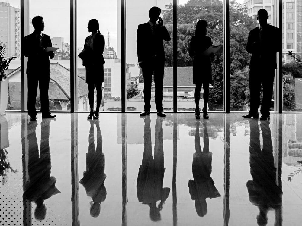 Silhouettes of business professionals standing in an office lobby.